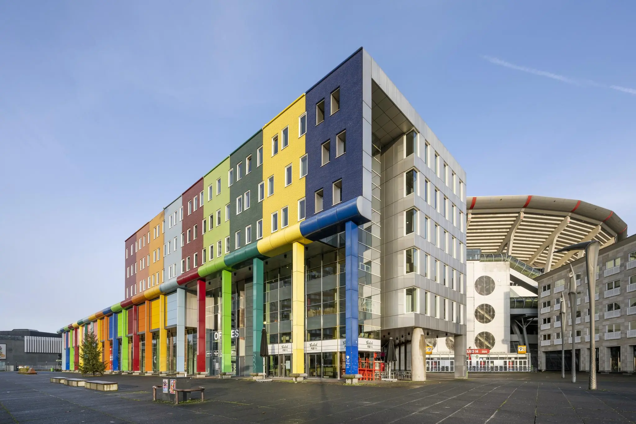 Kleurrijk kantoorgebouw aan de Johan Cruijff Boulevard met de Johan Cruijff ArenA op de achtergrond.